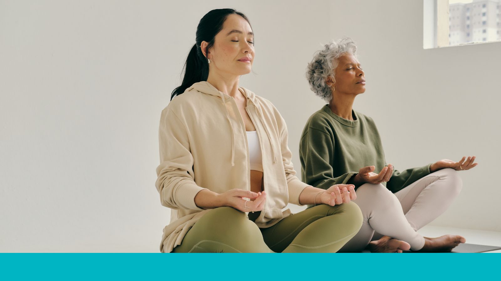 Two women with their eyes closed rest their forearms on their knees.