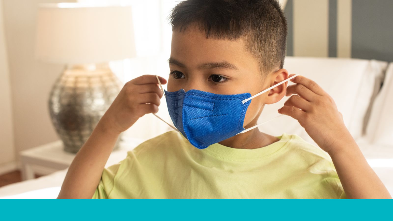 A young child puts on a protective face mask.