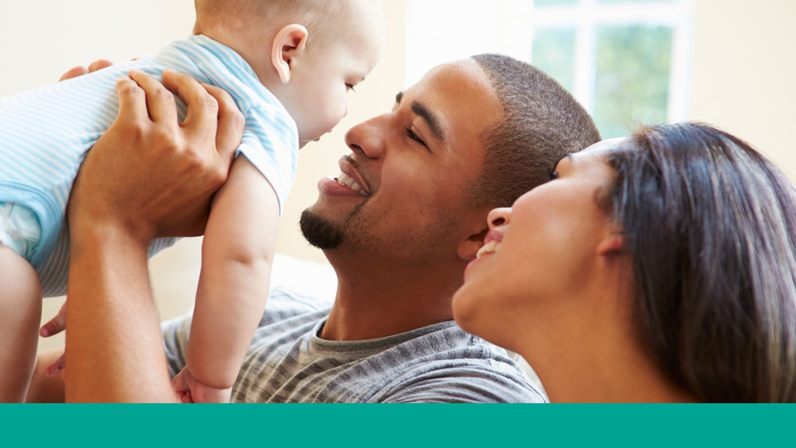 A man holds a baby and the woman next to him looks at the baby.